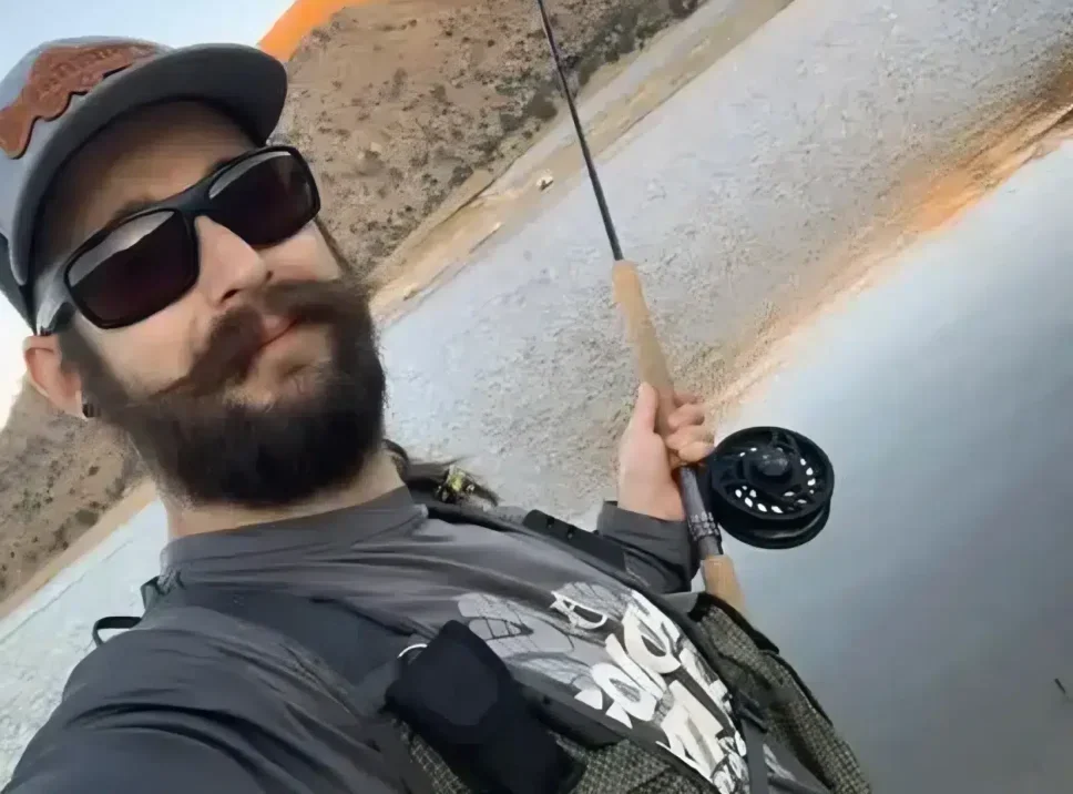 profile pic of hinkey chronicles man with a beard and sunglasses holding a fishing rod by a lake